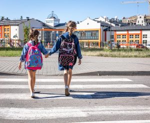 Two little girls holding hands while walking to an accessible school, showcasing safe routes and inclusive environments